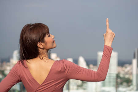 asian woman pointing up in urban environmentの写真素材