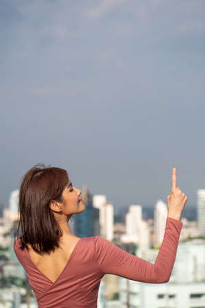asian woman pointing up in urban environmentの写真素材
