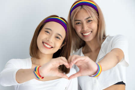 Proud non-binary LGBT couple forming heart hand gesture together, concept of diversity with same sex marriage, non-binary people togetherness, LGBT awareness, pride monthの写真素材