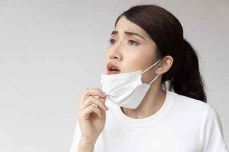 Tiring woman taking off face maskの写真素材