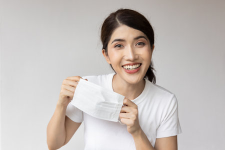 Happy smiling woman finally taking off face maskの写真素材