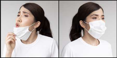 Suffocating young woman taking a breath out of face mask and still wearing face mask, concept image of long covid and post pandemic world, with or without maskの写真素材