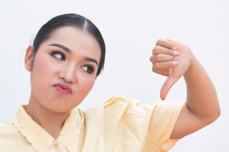 Woman pointing up disapproving thumb down hand gesture to blank spaceの写真素材