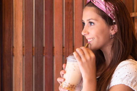 Happy Hispanic South American woman drinking Asian boba milk teaの写真素材