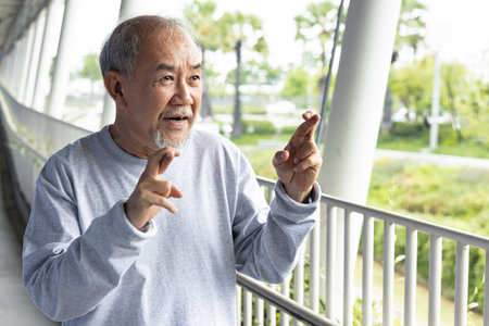 excited old senior man wishing with crossing finger expressionの写真素材