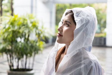 Woman wearing raincoat feeling refreshing rainfall in rainy monsoon seasonWoman wearing raincoat feeling refreshing rainfall in rainy monsoon seasonの写真素材