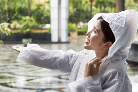 Woman wearing raincoat feeling refreshing rainfall in rainy monsoon seasonWoman wearing raincoat feeling refreshing rainfall in rainy monsoon seasonの写真素材