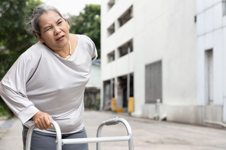 old senior woman with back pain using walking frame or walking aid device, concept of aging society health care, thin bone, osteoporosis or osteoarthritis symptomの写真素材