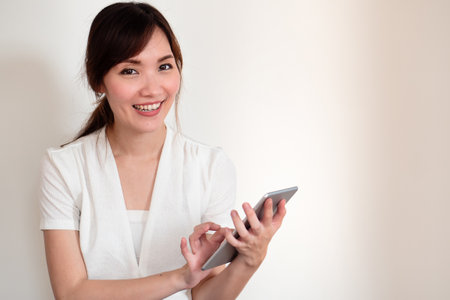 happy smiling young casual asian woman using computer tabletの写真素材