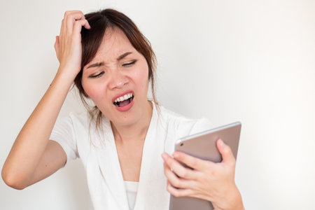 Upset angry asian woman using computer tablet showing negative disappointed expressionの写真素材