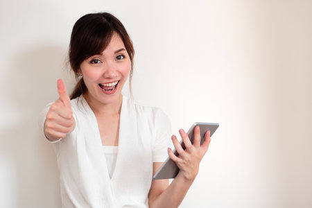 happy young casual asian woman using computer tablet showing thumb up gestureの写真素材