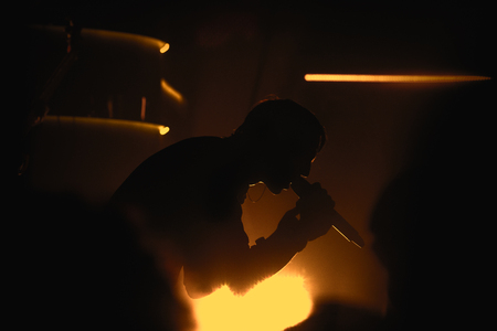 black silhouette of vocalist on rock concert, singing into a microphoneの写真素材