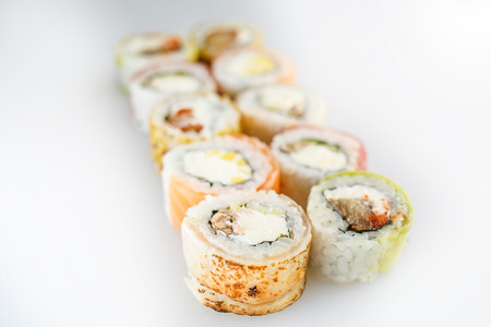 Sushi set. Rolls with salmon  and vegetables, vegetarian, on a wooden plate isolated on white backgroundの写真素材