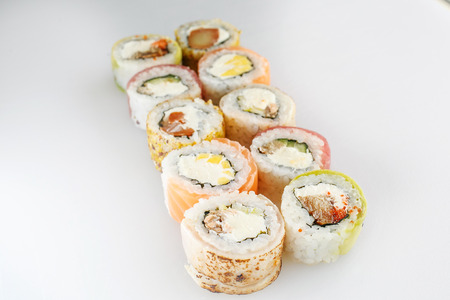 Sushi set. Rolls with salmon  and vegetables, vegetarian, on a wooden plate isolated on white backgroundの写真素材