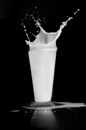 milk splash with glass on black backgroundの写真素材