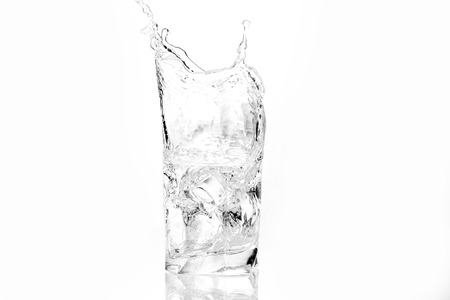 Ice cubes splashing into glass of water, isolated on whiteの写真素材