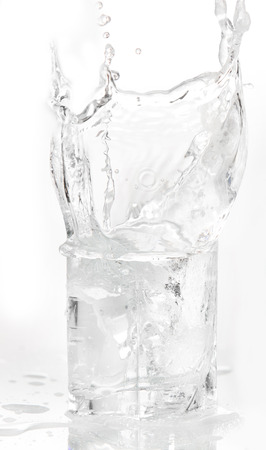 Ice cubes splashing into glass of water, isolated on whiteの写真素材