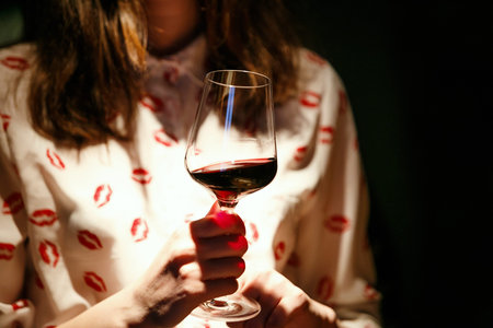 beautiful woman with glass red wine on black background
