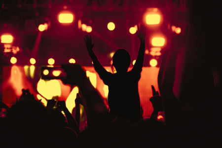 Black silhouette of young girl on rock concert, raised handsの写真素材
