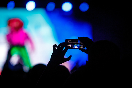 People makes photo with His smartphone on rock concert to share the moment with friends on social networksの写真素材