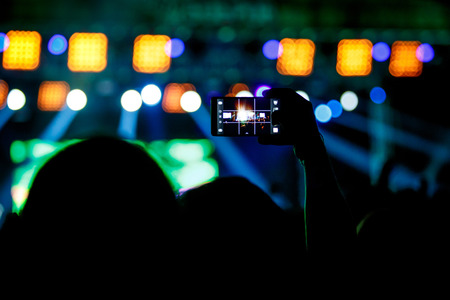 People makes photo with His smartphone on rock concert to share the moment with friends on social networksの写真素材