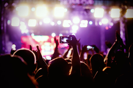 People makes photo with His smartphone on rock concert to share the moment with friends on social networksの写真素材