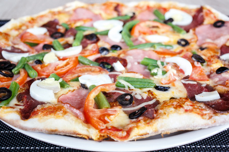 Close-up of Delicious Fresh Pizza with beans, cheese, ham and eggsの写真素材