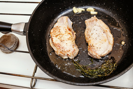 juicy pork steaks in the pan, top wiev of cooking foodの写真素材