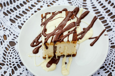 A square slice of cheesecake with dark and milk chocolate sauceの写真素材