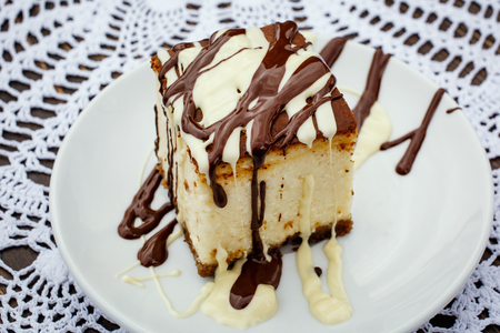 A slice of cheesecake with chocolate sauceの写真素材