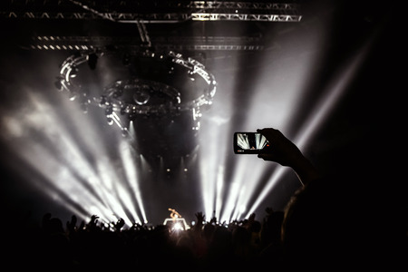 Hand with a smartphone records live music festival, Taking photo of rock concert stage, live concert, music festival, happy youth, luxury party, landscape exterior.の写真素材