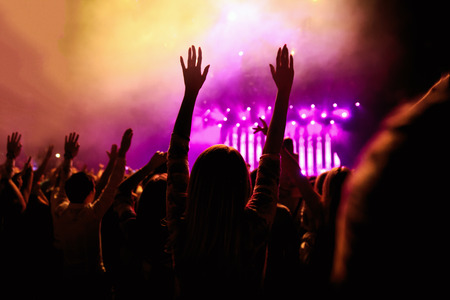 silhouettes of concert crowd in front of bright stage lightsの写真素材