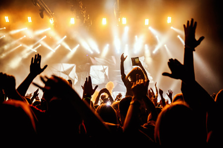 People black silhouettes of rock concert crowd in front of bright stage lightsの写真素材