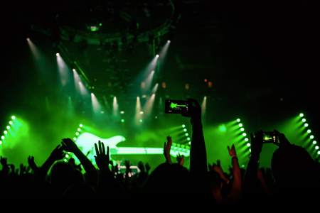 Rock concert crowd recording performance with digital smartphone, green guitar in stageの写真素材