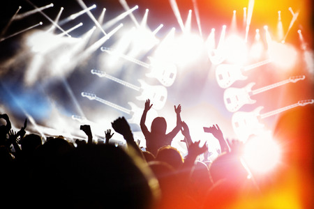 People black silhouettes of concert crowd in front of bright stage lights, guitar on stageの写真素材