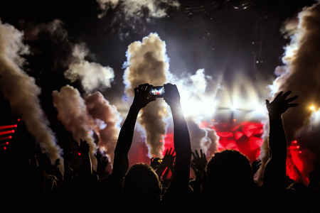 Take photo by smartphone in front of concert stage, during the light showの写真素材