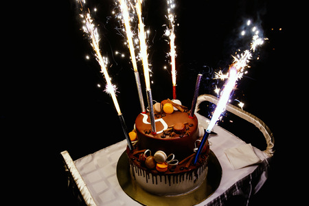 Birthday cake with fireworks on table in black backgroundの写真素材