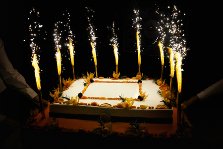 Rectangular Birthday fruit cake with fireworks candlesの写真素材