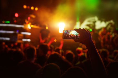 Hands with a smartphone records live music festival, live concert, show on stage