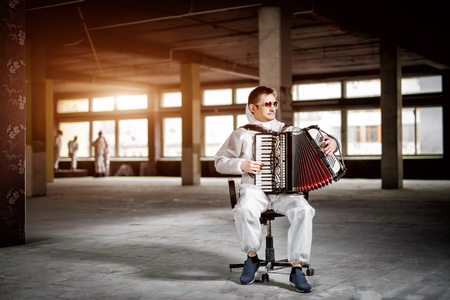 The musician playing the harmonica, accordion in the hall with columnsの写真素材