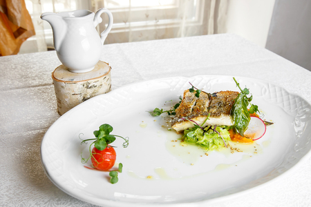 Fish dish - fried fish fillet of zander served with tomato, Radish and milk sauceの写真素材