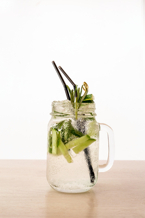 A cool drink of Mojito in Jar with a straw on the table. White backdroundの写真素材