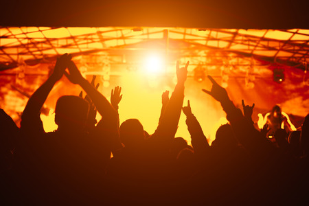 Silhouette of hands, cheering crowd at concertの写真素材