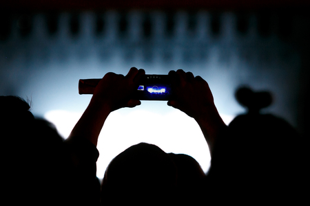 Video recording of the concert on the phone a smartphone. Back silhouette of handsの写真素材