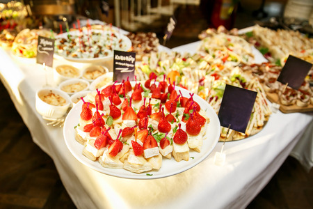 Event catering. Many dishes with cheese, meat, strawberries.