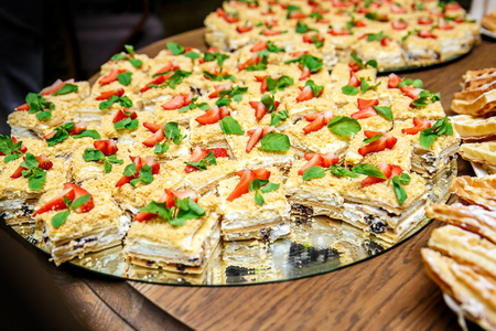 Napoleon cake filled with pastry cream on event catering decorated with fruits and flowers.の写真素材