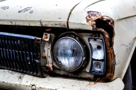 Detail of the front headlight of an rusty car outdoorの写真素材