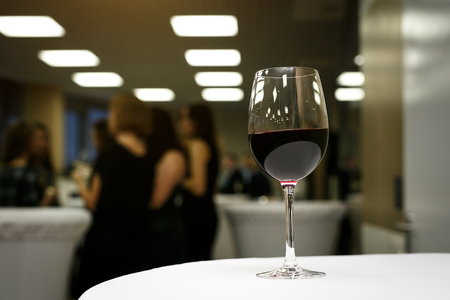 a glass of red wine on a white table in a working office.の写真素材