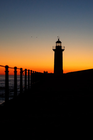 lighthouse on the ocean, silhouette at sunset, verticalの写真素材
