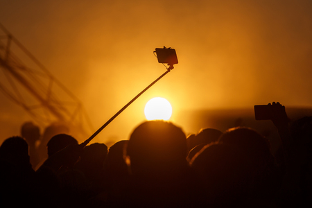silhouette of smartphone on selfie stick, sunsetの写真素材